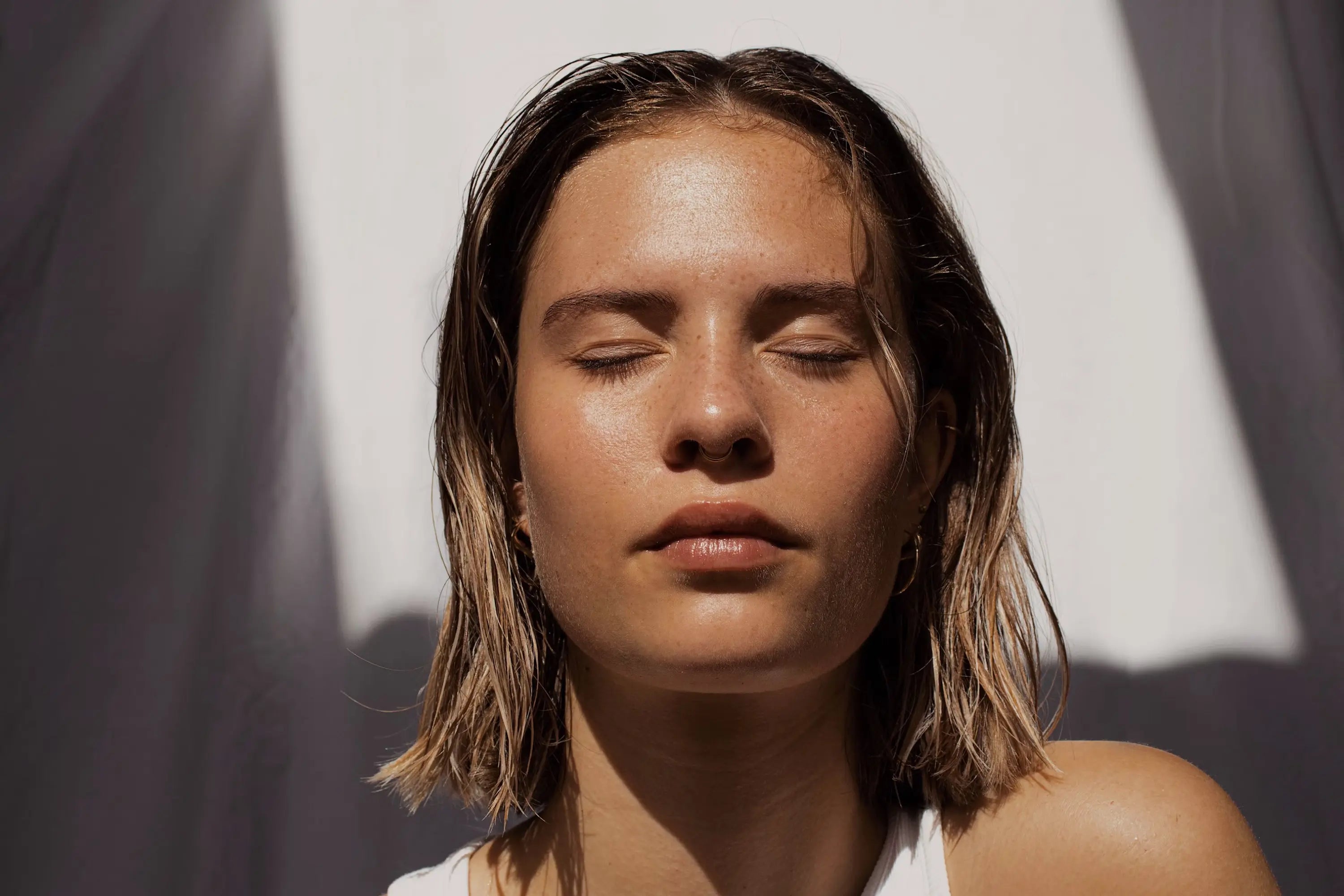 Woman with glowing, healthy skin basking in sunlight – natural skincare beauty shot with closed eyes and radiant complexion
